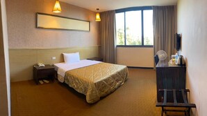A hotel room with a bed, bedside table, lamp, and a desk with a mirror. - Home Full Hotel (Jincheng)
