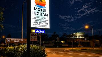 A motel sign with a moon in the background, a no vacancy sign, and a nearby restaurant.
