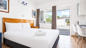 A hotel room with a bed, a desk, a chair, a microwave, and a view of the outside.