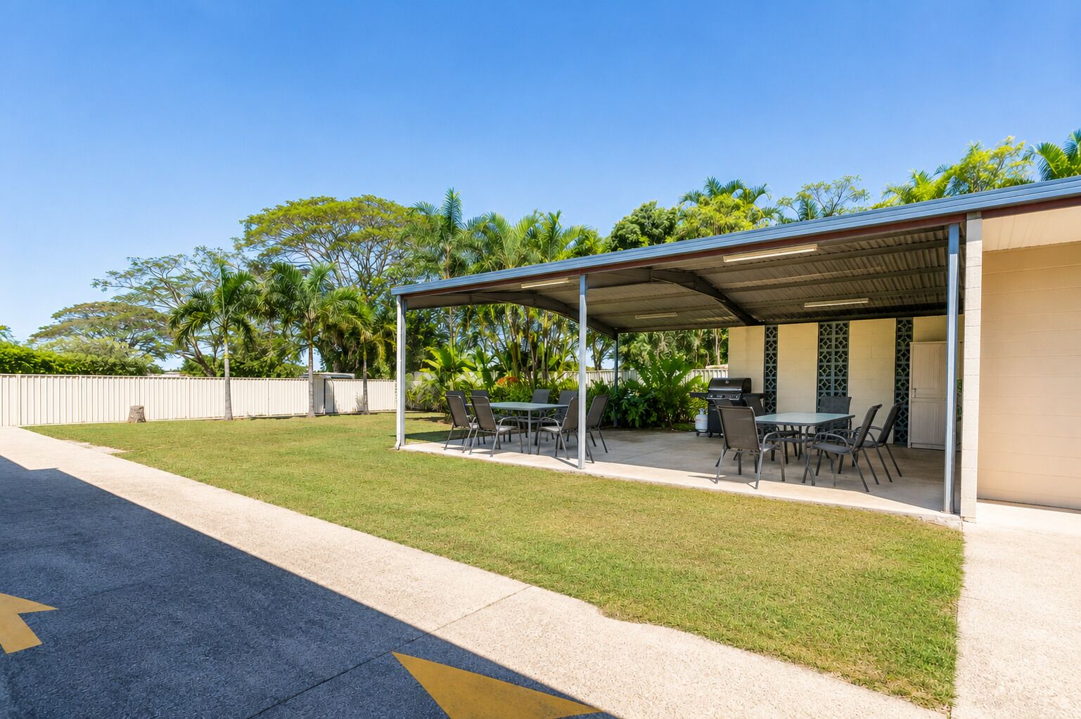 A covered outdoor patio with a grill, tables, and chairs.