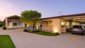 A motel with a reception area, a parking lot, and a car parked in front.