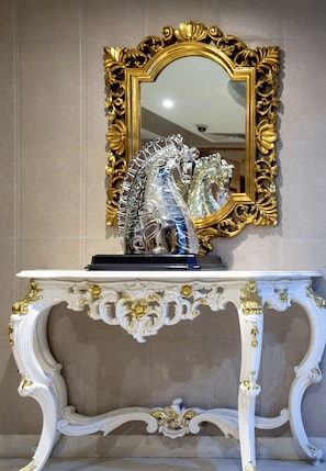 A white console table with gold accents and a gold-framed mirror above it. - De Sovrani (Bidhannagar)
