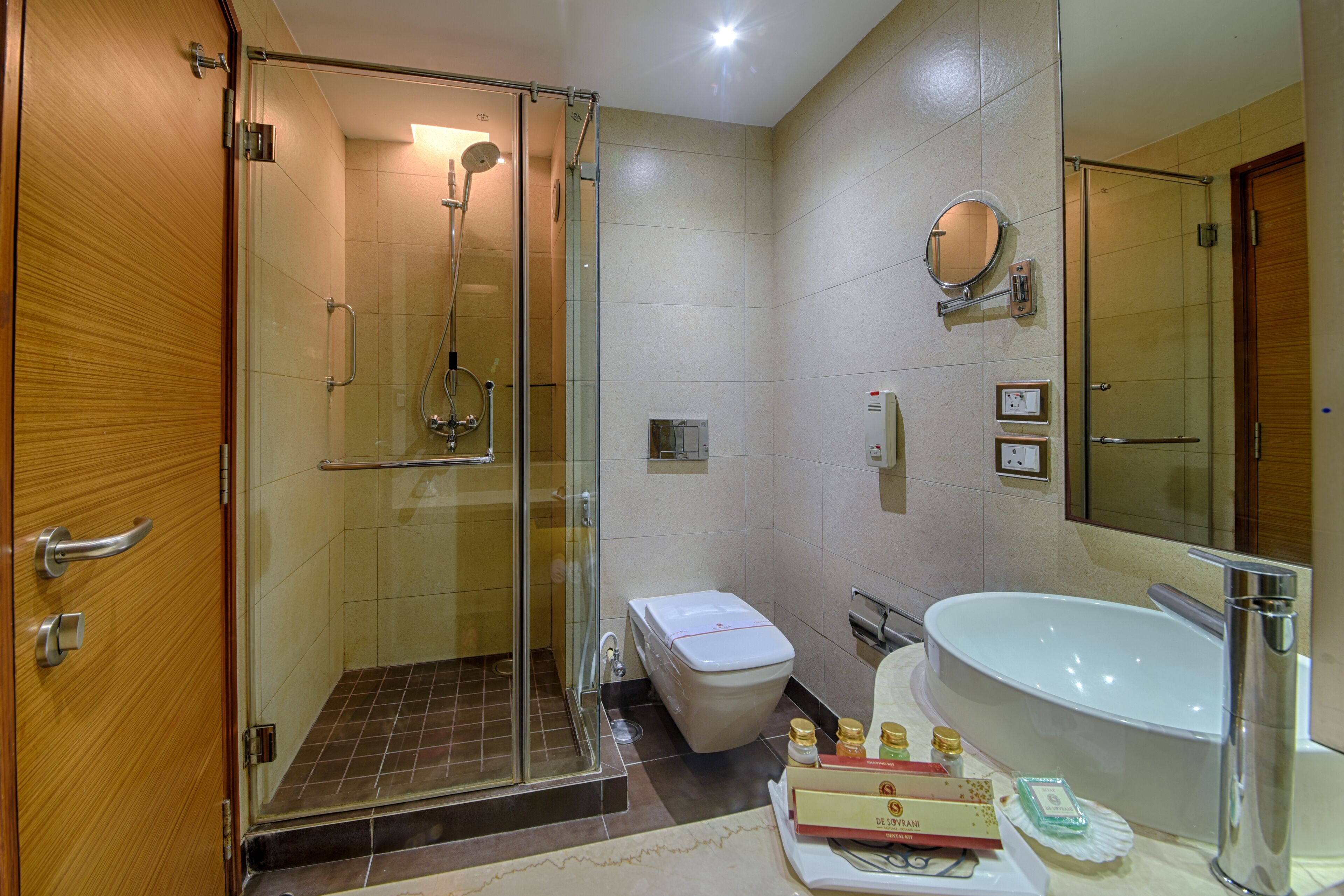 A modern bathroom with a glass-enclosed shower, a toilet, a sink, and a large mirror.