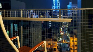 A balcony with a view of a lit tower and cityscape at night.