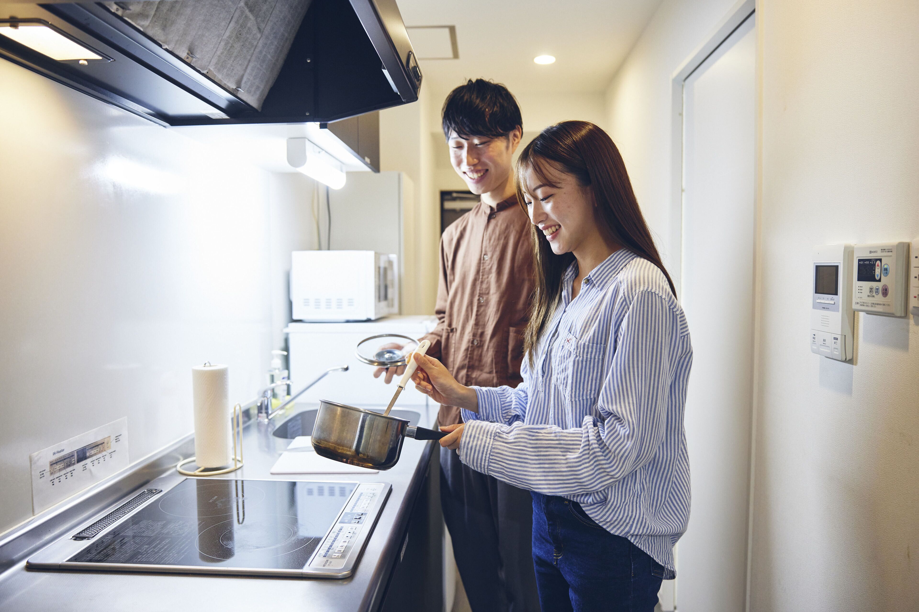 Una cocina moderna con estufa, microondas y un termostato digital en la pared.