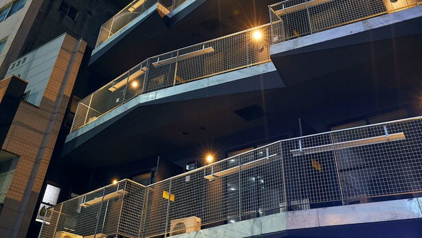 A multi-story building with balconies and exterior lighting.