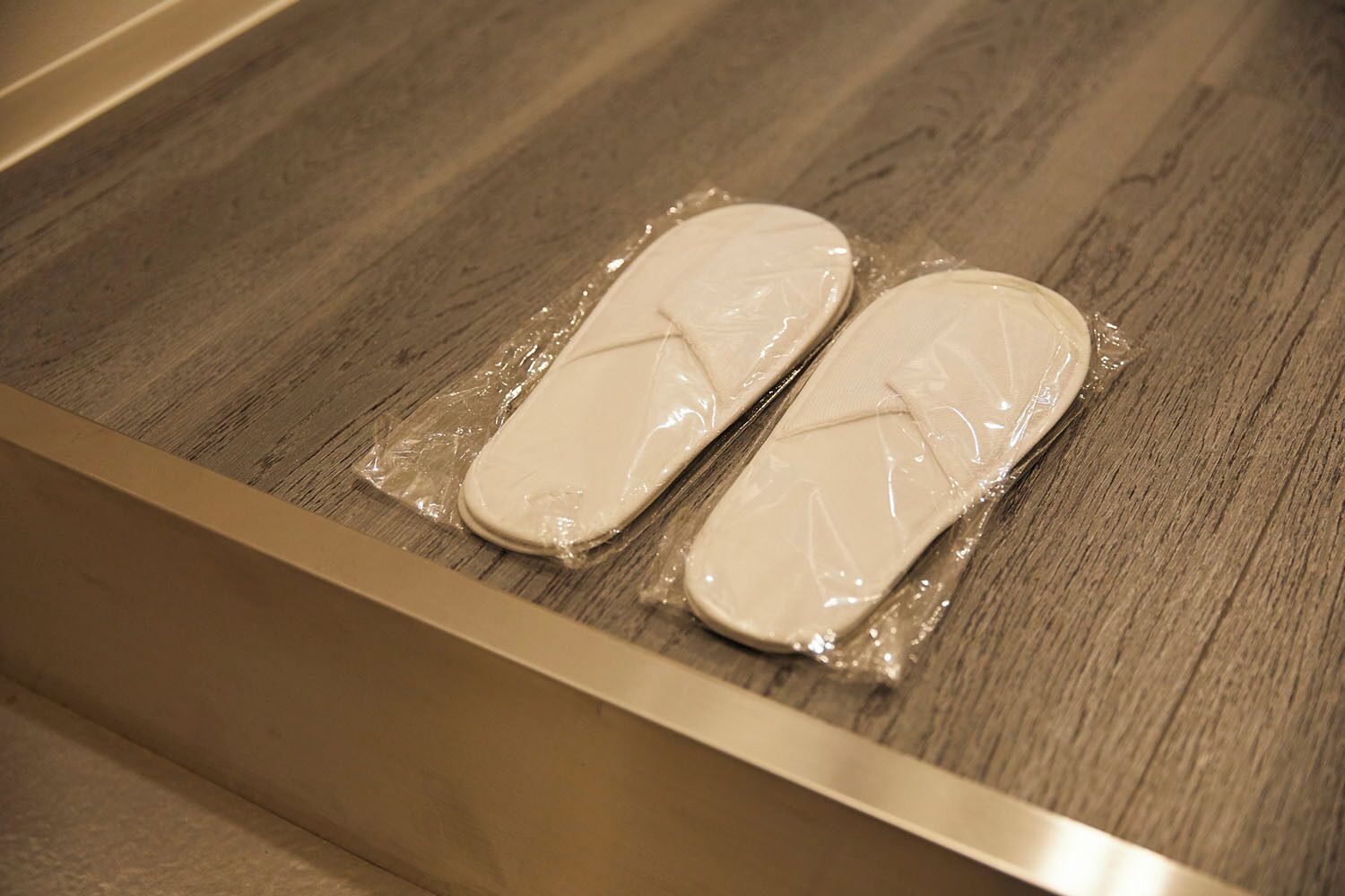 A wooden floor with a drawer containing a pair of white slippers.