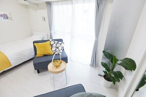 Ein Hotelzimmer mit Bett, Sofa, kleinem Tisch und einer Dekoration sowie einem Blumentopf.