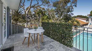 A balcony with a table and chairs, a swimming pool, and a hedge. - Balmoral Cabana - only 150m to Balmoral Beach (Mosman)