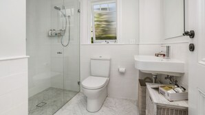 A modern bathroom with a glass-enclosed shower, a white toilet, and a sink with a mirror above it. - Balmoral Cabana - only 150m to Balmoral Beach (Mosman)