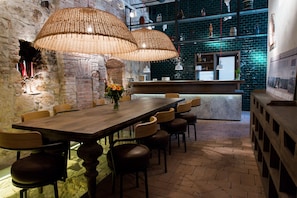 A restaurant with a long wooden table, multiple chairs, wicker pendant lights, a brick wall, and a tiled backsplash. - Guest House 1568 (Cluj-Napoca)
