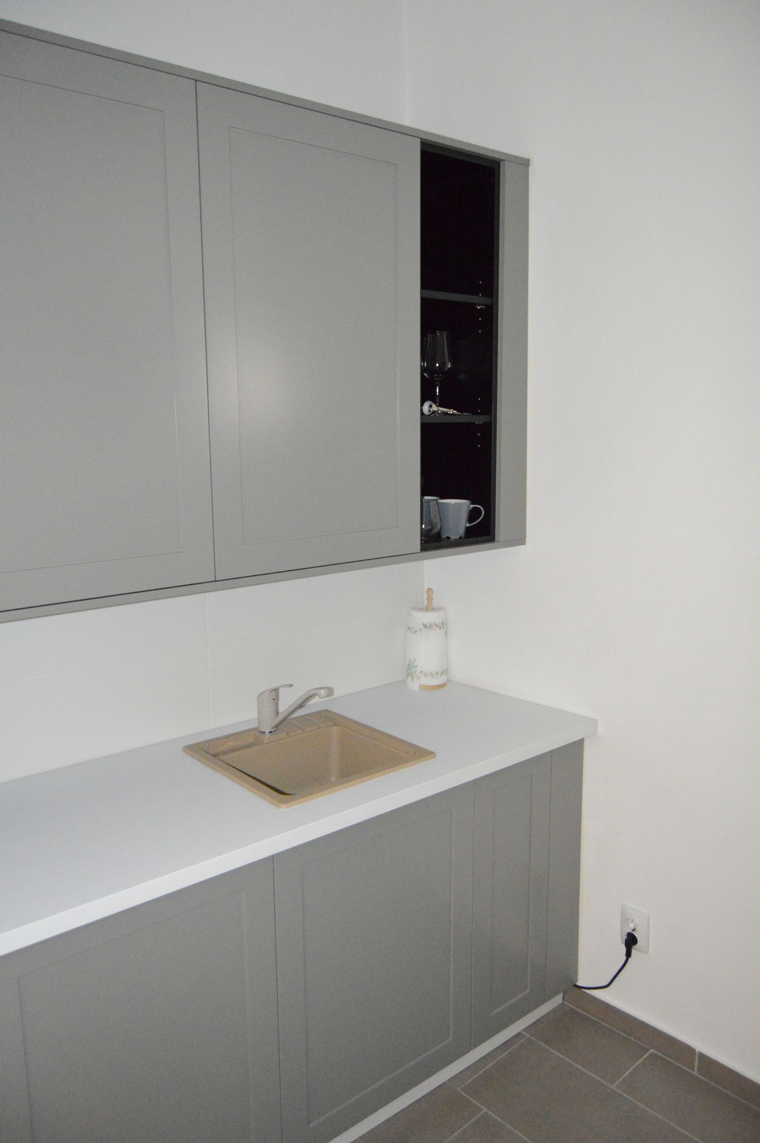 A kitchen with a white countertop, a stainless steel sink, and a window above the sink.