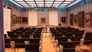 A conference room with rows of chairs, a podium, and framed portraits on the walls. - Guest House 1568 (Cluj-Napoca)