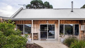 Un bâtiment moderne doté d’un toit en métal, d’une façade en bois et de grandes fenêtres.