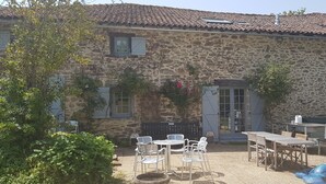 A stone house with a patio area featuring outdoor furniture and a barbecue grill.