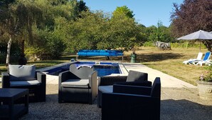 A backyard with a swimming pool, outdoor furniture, and a covered barbecue area.