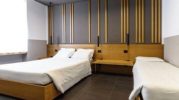 A modern hotel room with a large bed, a smaller bed, and a wooden headboard.