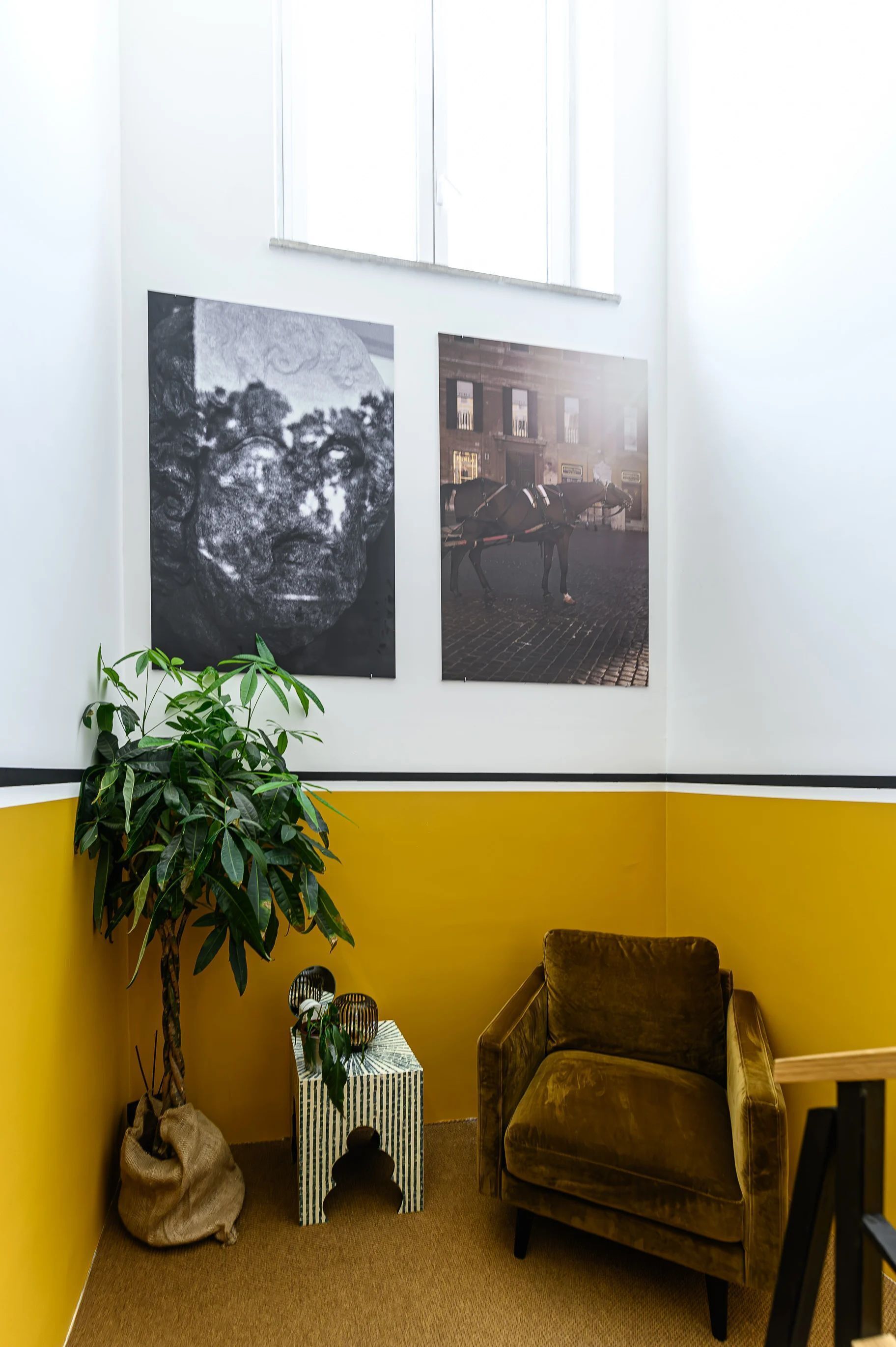 A room with a yellow wall, a brown armchair, a small table, and a potted plant.