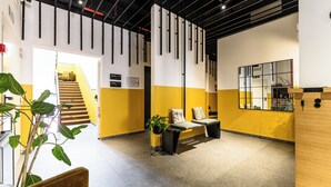 A modern lobby with a staircase, a reception desk, and a seating area with a plant. - Hotel Central Lodge (Rome)