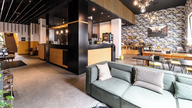 A modern hotel lobby with a bar area, seating arrangements, and a staircase leading to another level. - Hotel Central Lodge (Rome)