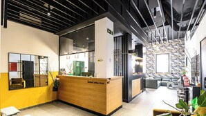 A hotel reception area with a wooden reception desk, a seating area with sofas, and a decorative wall with a floral pattern. - Hotel Central Lodge (Rome)