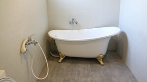 Un baño con una bañera independiente, ducha e inodoro.