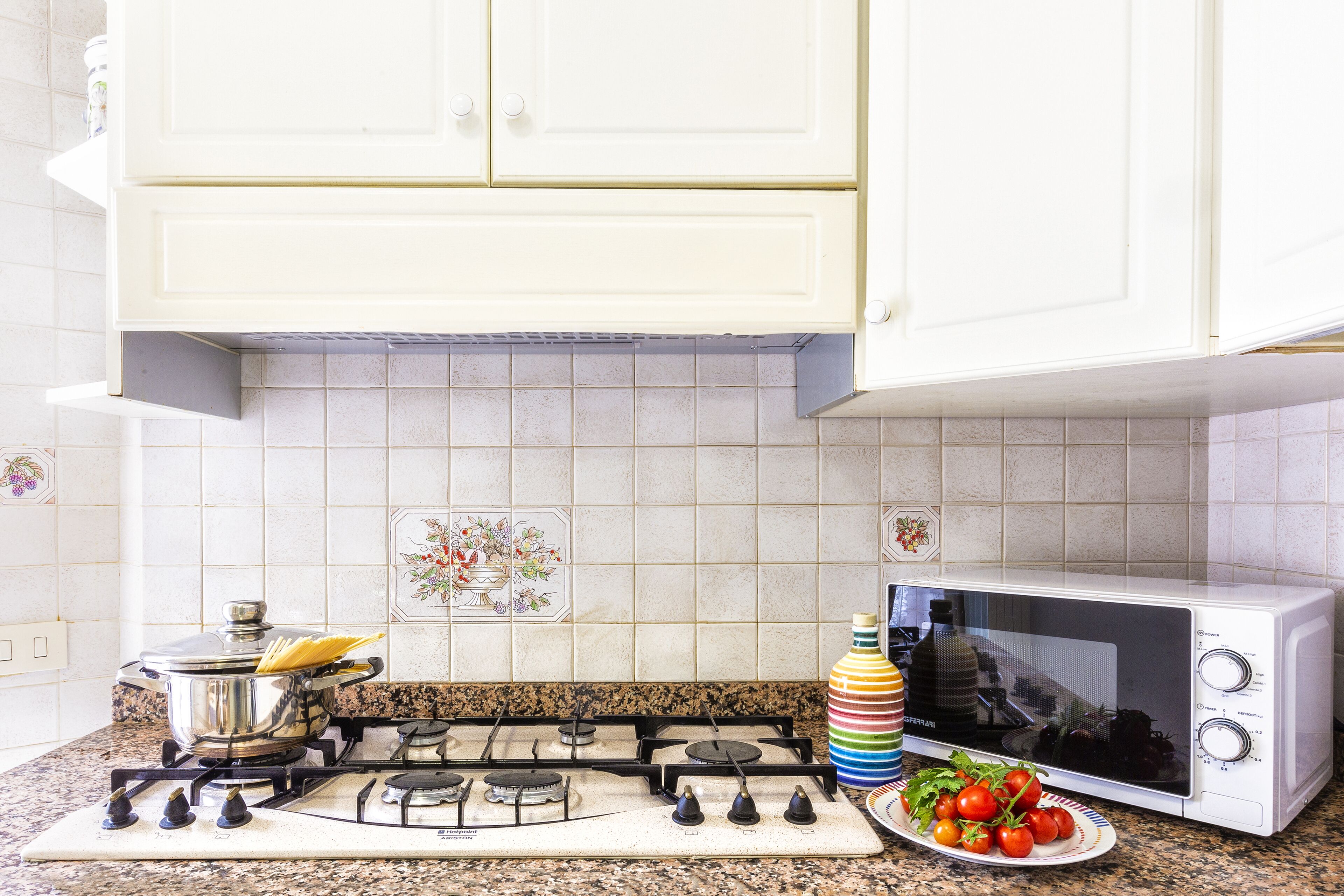 A kitchen with a gas stove, a microwave, and a tiled backsplash.