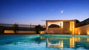 A swimming pool with clear water, a crescent moon in the sky, and a small building with a door and two chairs. - T2-2º vista mar, piscina, bbq, para a praia vai a (Albufeira)