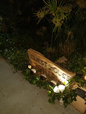 A wooden sign with the inscription "GUEST HOUSE" surrounded by greenery and illuminated by small lights. - Guest House Roki & Diva - Adults only (Zadar)
