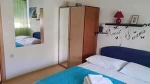 A bedroom with a bed, a wardrobe, a mirror, and a shelf with decorative items. - Guest House Roki & Diva - Adults only (Zadar)