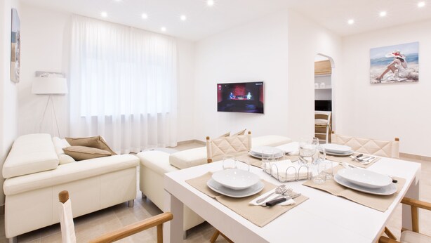 A modern living room with a dining area, white furniture, a flat-screen TV, and a painting on the wall. - Style House a few step from Sorrento main square (Sorrento)