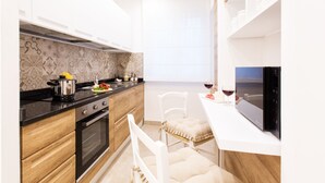 A modern kitchen with a stove, oven, and countertop with cooking utensils. There is a dining area with a chair and a table. - Style House a few step from Sorrento main square (Sorrento)