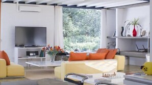 Un soggiorno moderno con una grande TV a schermo piatto, posti a sedere confortevoli e un'area pranzo con tavolo in vetro.