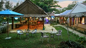 An outdoor seating area with thatched-roof structures, tables, and chairs. - Hoi An Blue Seaside Homestay (Da Nang)