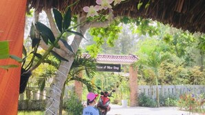 A covered outdoor area with a thatched roof, a sign reading "Have a Nice Day", and a pathway leading to a building. - Hoi An Blue Seaside Homestay (Da Nang)