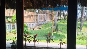 A room with a view of a thatched-roof structure and a bamboo fence outside. - Hoi An Blue Seaside Homestay (Da Nang)