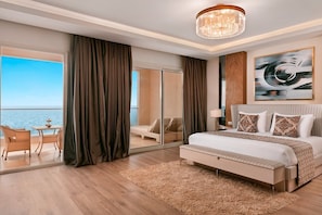 Una habitación de hotel moderna con una cama grande, vistas al mar, un balcón con mobiliario de mimbre y un candelabro.