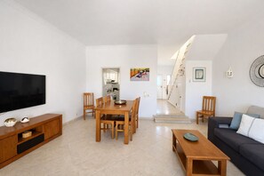 Una sala moderna con televisor de pantalla plana, mesa de comedor de madera y un sofá.
