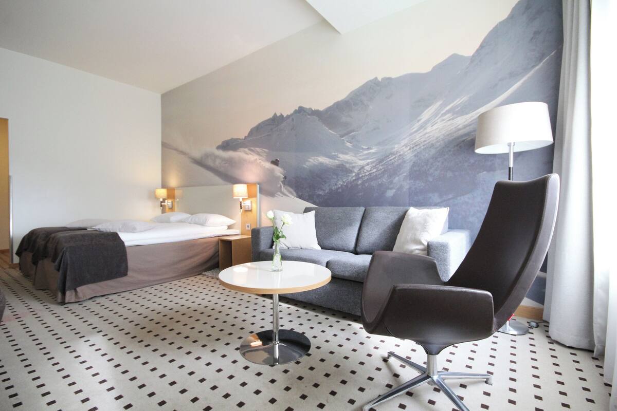 A hotel room with a bed, a sofa, a round table, and a chair.
