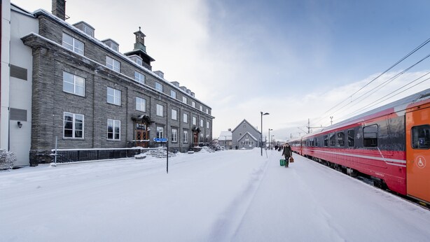Una estación de tren cubierta de nieve con un tren rojo en el andén.
