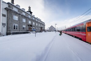 A snow-covered train station with a red train on the platform. - Oppdal Turisthotell (Oppdal)