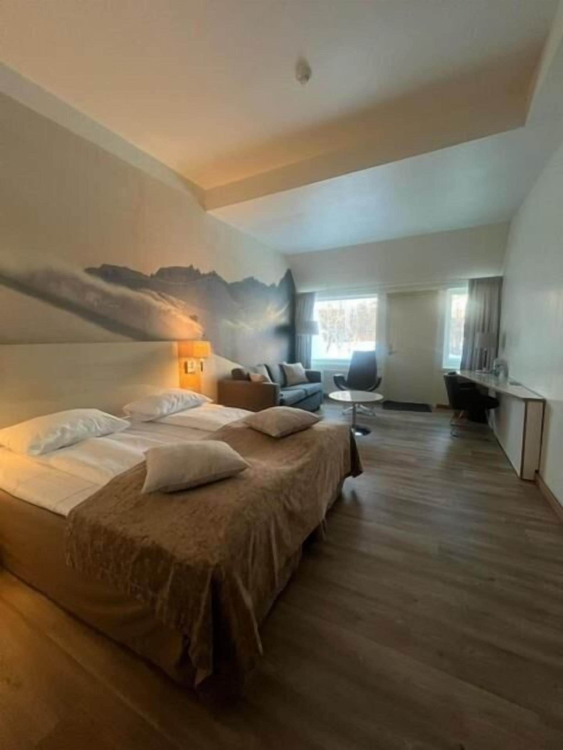 A hotel room with a large bed, a desk, and a view of the outdoors.