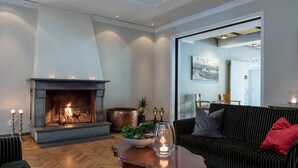 Una sala de estar con chimenea, un sofá, una mesa de centro y un comedor al fondo.