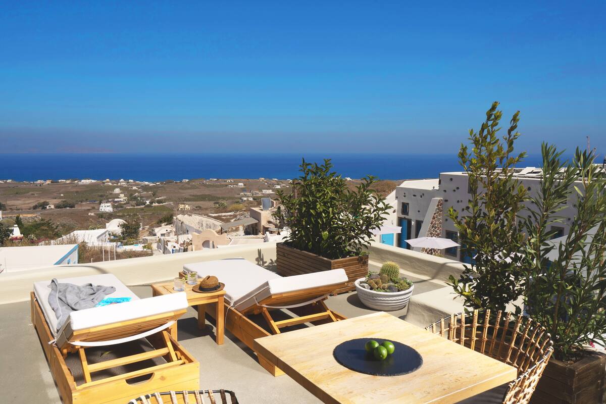 Una terraza en la azotea con sillones de descanso, una mesa de madera y plantas en macetas.