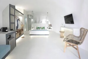 Un dormitorio moderno con cama, televisor, silla y escritorio con computadora.