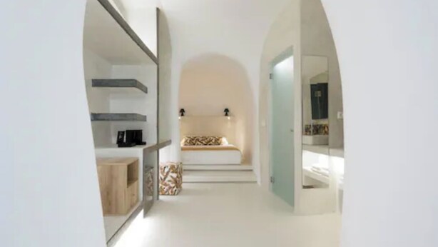Habitación de hotel moderna con diseño minimalista, que incluye una cama con ropa de cama estampada, una mesita de noche y una unidad de estanterías empotrada.