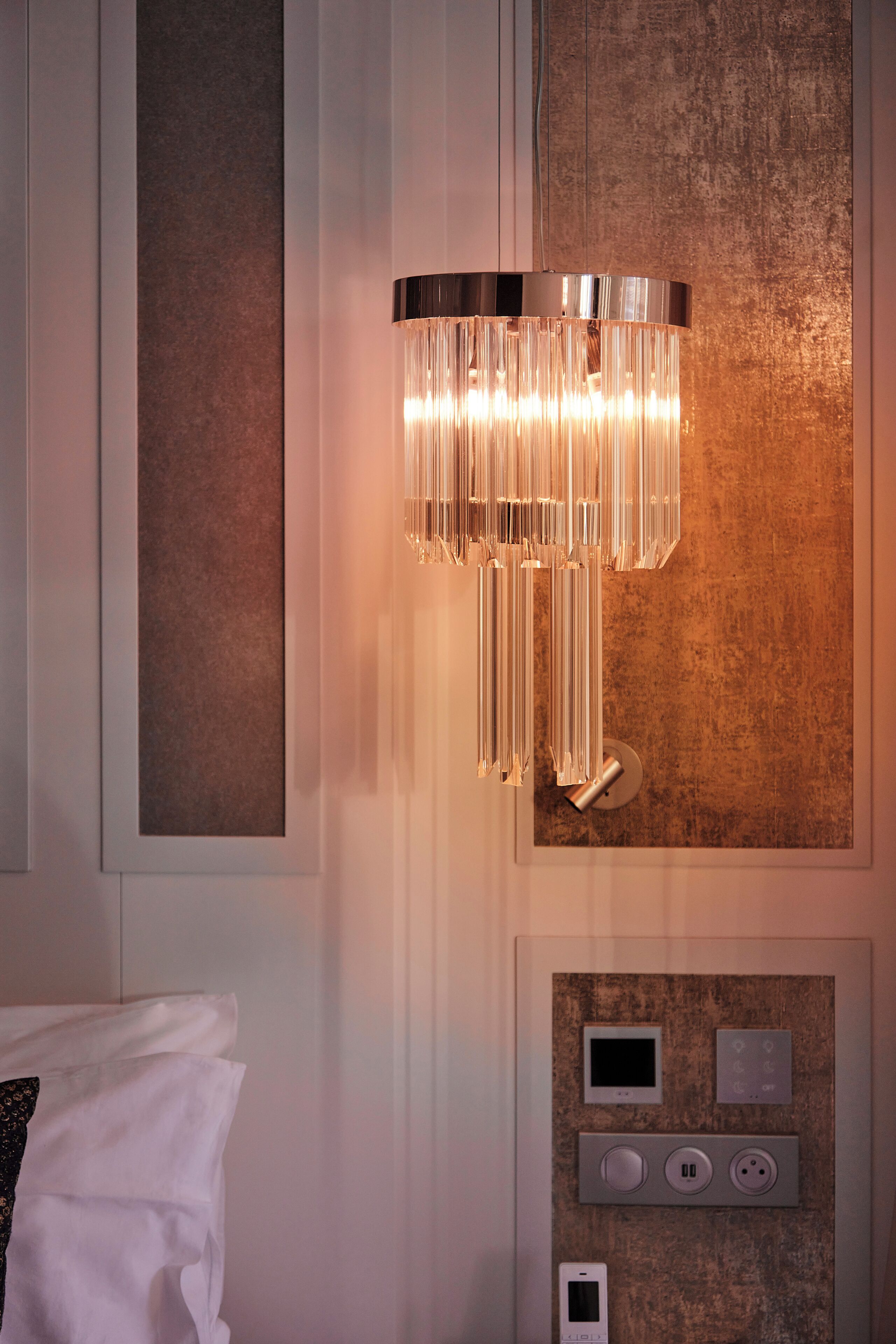 A modern bathroom with a wall-mounted light fixture, a towel rack, and a control panel.