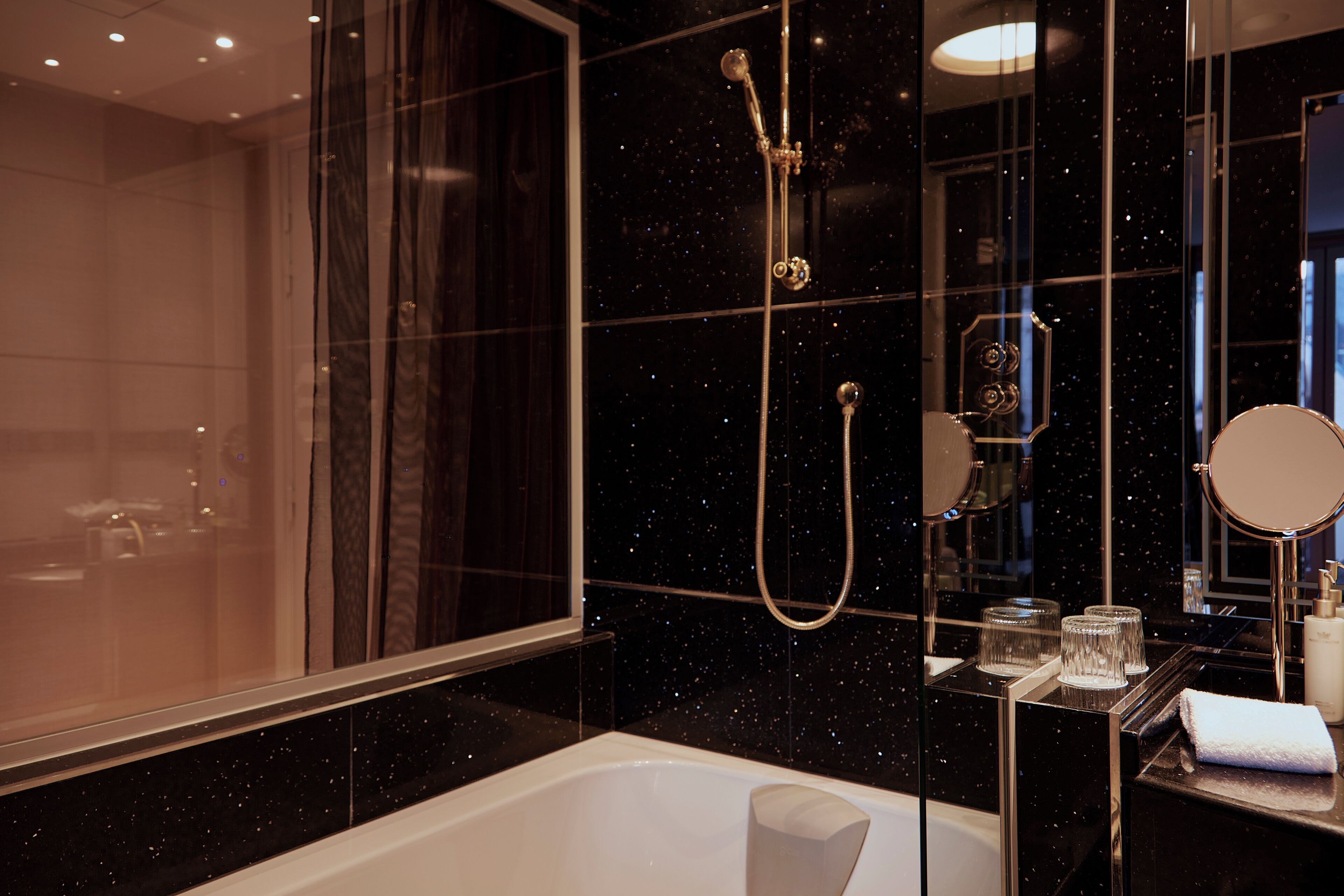 A modern bathroom with a large mirror, a bathtub, and a shower with a handheld showerhead.