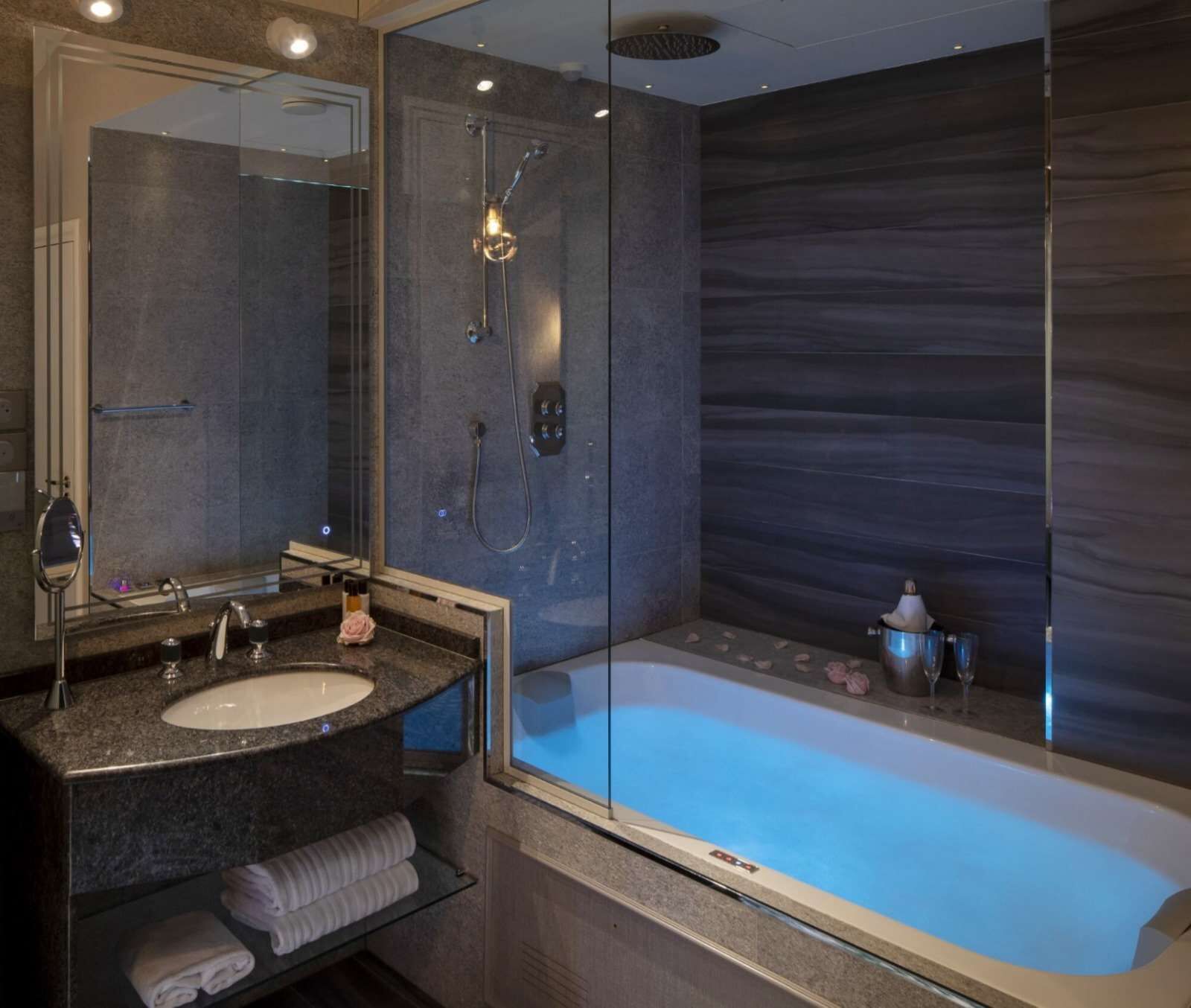 A modern bathroom with a glass-enclosed shower, a standalone bathtub, and a vanity with a sink and mirror.