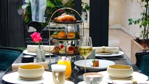 A table set for a meal with a tiered dessert stand, a glass of white wine, and a flower. - Paris j'Adore Hotel & Spa (Paris)